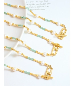 Détail d'un collier vintage avec perles, perles vertes et fermoir à bascule doré