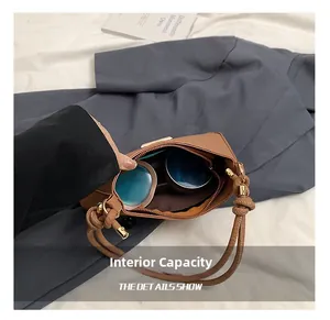 Internal capacity of brown leather shoulder bag showing makeup and mobile phone inside