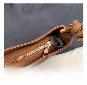 Detailed close-up of premium gold zipper and chevron stitching on brown shoulder bag
