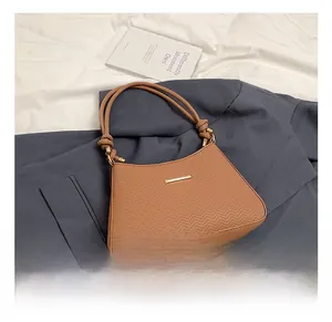 Detail of camel brown shoulder bag with V-shaped embossing and gold metal clasp