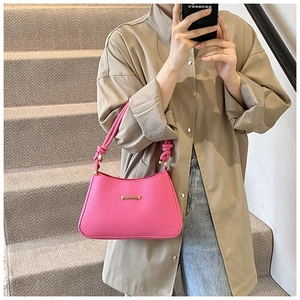 Bright pink woven shoulder bag with gold metal detail shown in a mirror selfie