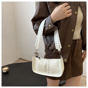 Gros plan du sac à bandoulière à rivets beige porté avec une veste en cuir marron chic