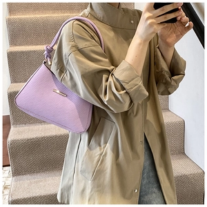 Detail of purple woven underarm bag with knot strap and gold metal buckle on model