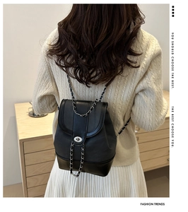 Detail of elegant black PU leather backpack featuring silver chain strap and metal swivel lock