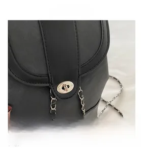Detail of black textured leather bag featuring silver oval twist lock and interwoven chain