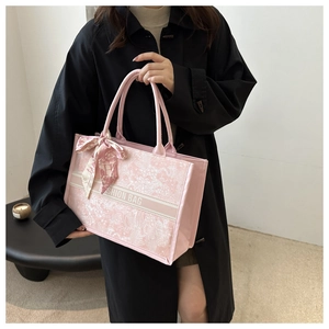 Details einer rosa Tragetasche mit floralem Muster und stilvollem Markenschriftzug