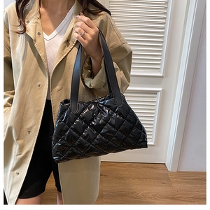 Detail of black quilted puffer tote bag with glossy finish and sleek shoulder straps