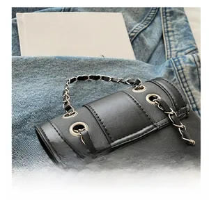 Detail view of black crossbody bag with silver eyelet studs and metal chain straps