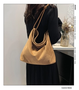 Detail of camel suede hobo bag with unique knotted strap on shoulder of a model