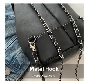 Close-up of leather chain strap with polished silver metal hook on a black bag