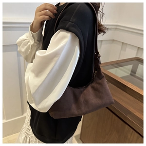 Detail of a dark brown suede crescent tote bag with smooth zipper and matte finish