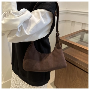 Detail of dark brown suede hobo bag with vintage stitching shown on model's shoulder