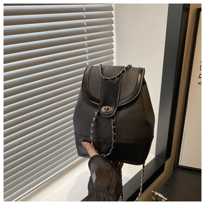 Detail of gray canvas and black leather patchwork bag with silver chain strap and metal lock