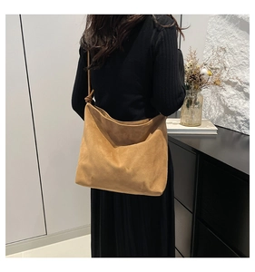 Back view of a model wearing a dark brown oversized suede hobo tote bag with knot detail