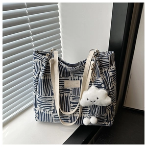 Detail of canvas tote bag with blue geometric pattern and white cloud plush charm