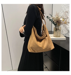 Close-up of a large brown suede tote bag with knotted shoulder strap detail