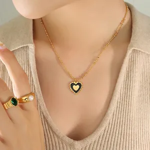 Gold double-sided heart pendant necklace with pearl and emerald ring set worn by model