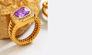 Detail eines goldenen Cocktailrings mit lila Edelstein und geflochtenem Ringband