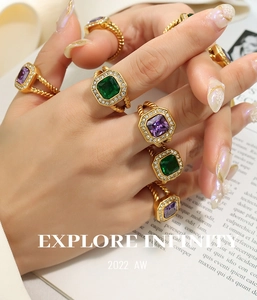 Detailansicht goldener Ringe mit lila und grünen Schmucksteinen und gedrehter Ringschiene