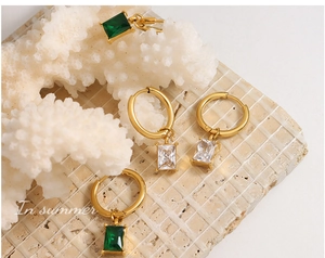 Detail of gold-plated earrings with emerald green and clear square-cut crystals