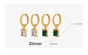 Detail view of gold hoop earrings with white and emerald green zircon rectangular pendants