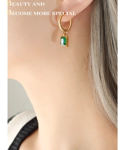 Detail of vintage gold plated hoop earrings with a rectangular green zircon pendant