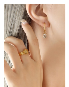 Detail of gold-plated hoop earring with zircon pendant and vintage buckle ring
