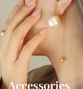 Détail des boucles d'oreilles à perle blanche avec pompon chaîne dorée et bague assortie