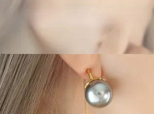 Gros plan d'une boucle d'oreille chaîne en or avec perle grise portée par un mannequin