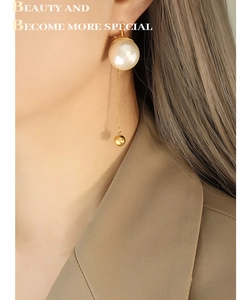 Détail de boucles d'oreilles perles longues avec chaîne dorée portées par un mannequin