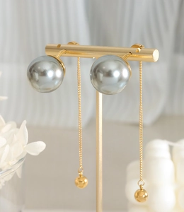 Détail de boucles d'oreilles chaînes dorées avec perles gris-argent et pendentifs boules