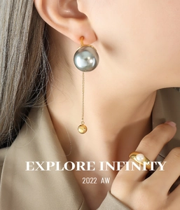 Détail de boucles d'oreilles dorées à franges avec perles grises et bague assortie