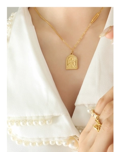 Détail du pendentif religieux doré et bague taille émeraude avec haut orné de perles