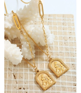 Détail du pendentif portrait doré vintage sur une chaîne à maillons mixtes texturée