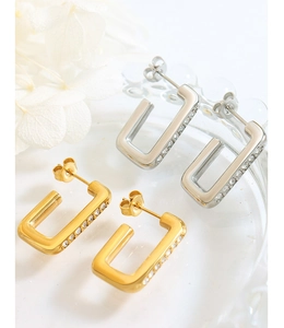 Dettaglio macro di orecchini geometrici a U in oro e argento con pietre di zircone