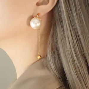 Boucles d'oreilles pendantes en perles blanches et chaîne dorée sur mannequin