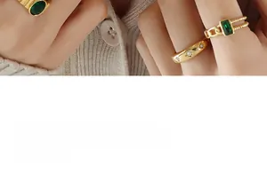 Detail von Vintage-Goldringen mit grünen Smaragden und Sternengravur am Finger