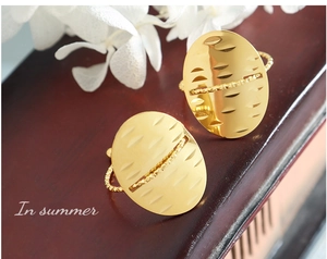 Detailed close-up of a gold oval ring with textured surface and twisted rope band design