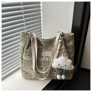 Detail of green and white striped woven tote bag with leather straps and cloud pendant