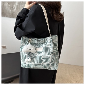 Detail of green and white woven tote bag with a cute white cloud plush pendant