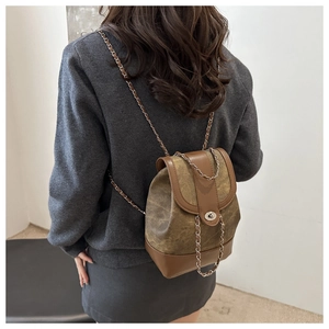 Detail of vintage canvas and leather backpack with chain strap on female model