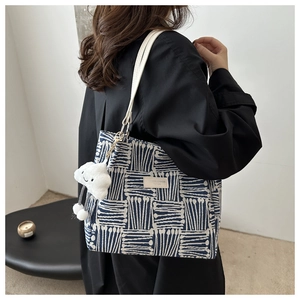 Detail of blue and white striped tote bag with plush cloud charm and slim shoulder straps