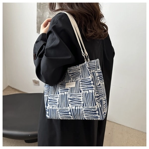 Detail of canvas tote bag featuring blue geometric patterns and slender leather straps