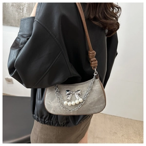 Détail du sac bandoulière en denim avec chaînes argentées, perles et nœud décoratif