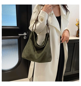Close-up of knotted rope handle on deep green suede tote bag with matte finish