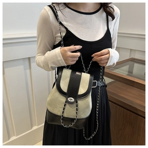 Detail of canvas shoulder bag with black leather flap and silver chain strap