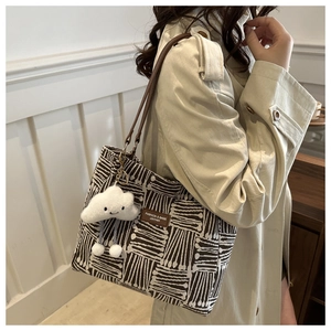 Detailed view of woven tote bag featuring leather straps and cute cloud charm accessory