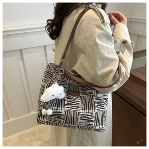 Detail of large woven tote bag with brown geometric patterns and leather straps