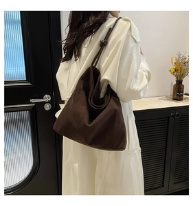 Detailed view of the knotted shoulder strap on a brown suede tote bag in a lifestyle setting