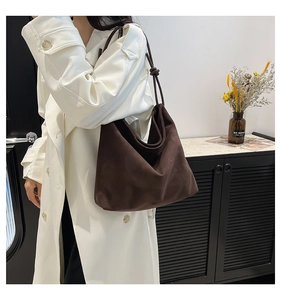 Detail of deep brown suede tote bag featuring a minimalist knotted shoulder strap design